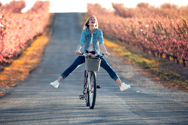 Une femme avec les jambes qui ne touches plus les pédales du vélo dans un champ en fleur