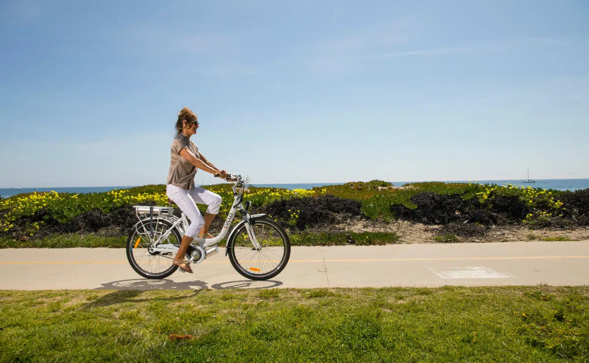 une femme fait du vélo en été au bord de la plage